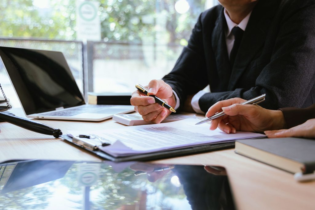 Two attorneys reviewing legal contract documents at a law office desk