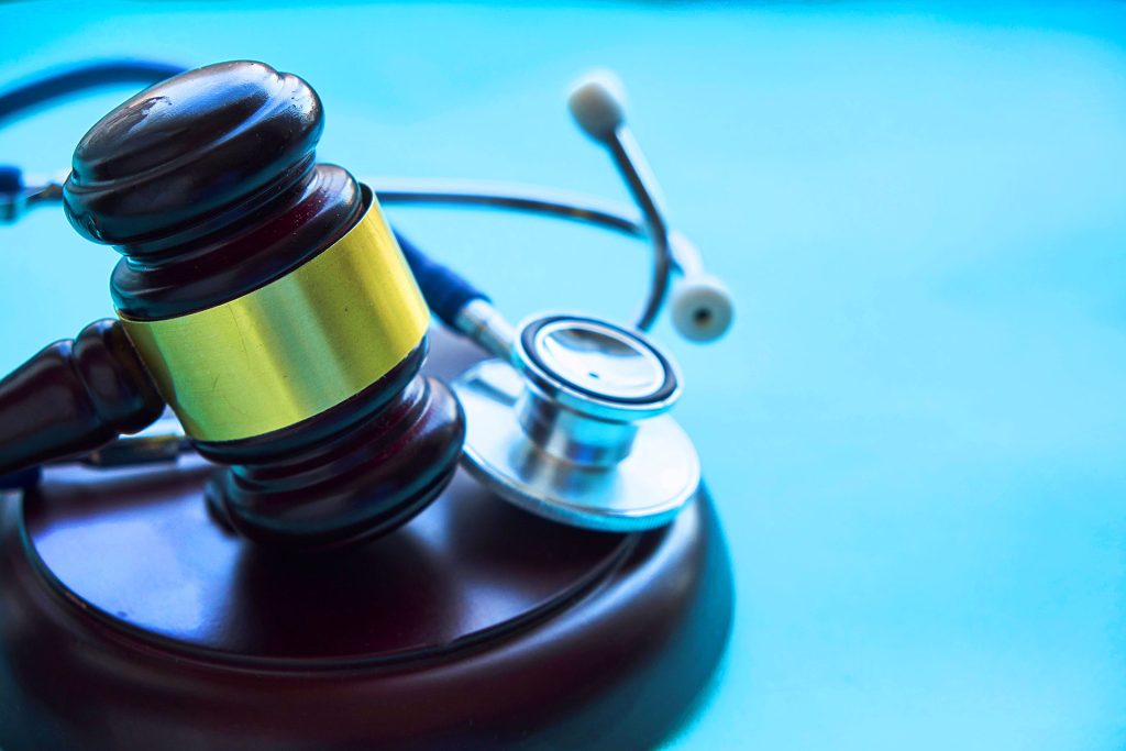 Judge gavel and stethoscope on blue background symbolizing medical legal case