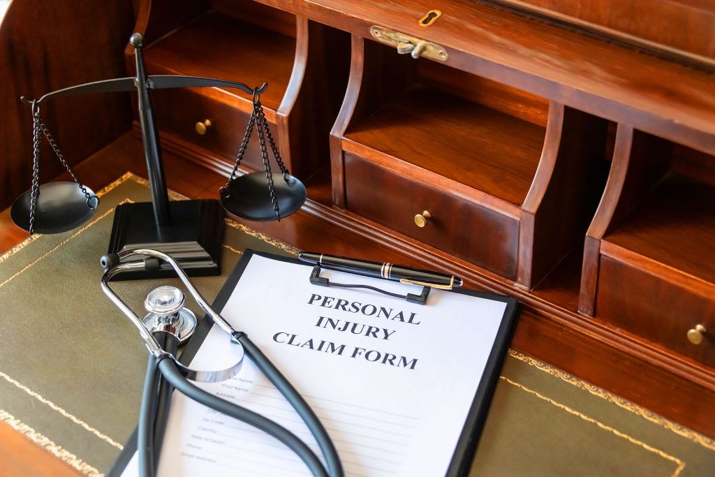 Personal injury claim form with stethoscope and justice scale