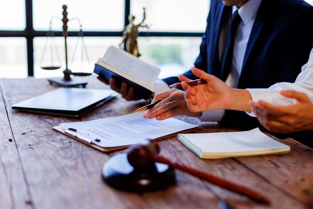 Attorney holding law book while discussing contract with client