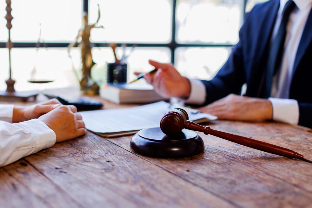 Lawyer and client reviewing documents with gavel on desk